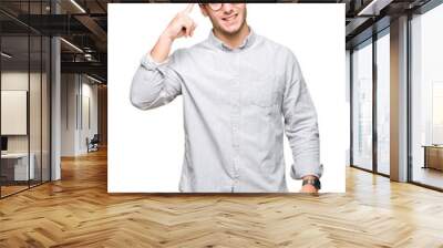 Young handsome man wearing glasses over isolated background Smiling pointing to head with one finger, great idea or thought, good memory Wall mural