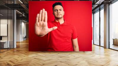 Young handsome man wearing red casual polo standing over isolated background doing stop sing with palm of the hand. Warning expression with negative and serious gesture on the face. Wall mural