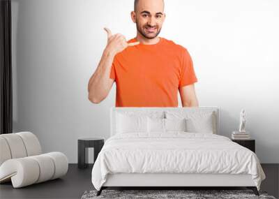 Young handsome man wering casual t shirt smiling doing phone gesture with hand and fingers like talking on the telephone. communicating concepts. Wall mural