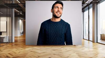 Young handsome man with beard wearing casual sweater standing over white background looking away to side with smile on face, natural expression. Laughing confident. Wall mural