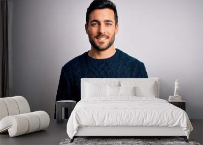 Young handsome man with beard wearing casual sweater standing over white background with a happy and cool smile on face. Lucky person. Wall mural