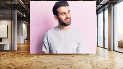 Young handsome man with beard wearing casual t-shirt looking to side, relax profile pose with natural face and confident smile. Wall mural