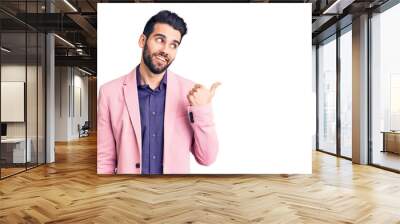 Young handsome man with beard wearing elegant jacket smiling with happy face looking and pointing to the side with thumb up. Wall mural