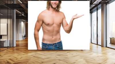 Young handsome shirtless man with long hair showing sexy body over isolated background smiling cheerful presenting and pointing with palm of hand looking at the camera. Wall mural