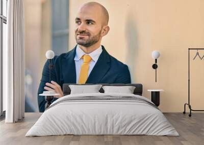 Young hispanic bald businessman with arms crossed smiling happy at the city. Wall mural