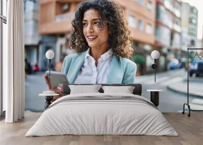 Young hispanic business woman wearing professional look smiling confident at the city using smartphone Wall mural