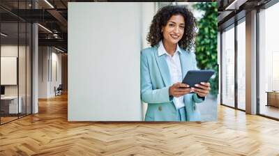 Young hispanic business woman wearing professional look smiling confident at the city using touchpad device Wall mural