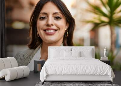 Young hispanic businesswoman smiling happy standing at the city. Wall mural