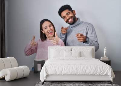 Young hispanic couple standing together pointing fingers to camera with happy and funny face. good energy and vibes. Wall mural