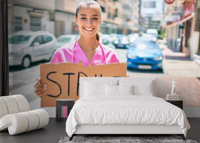 Young hispanic doctor woman smiling happy holding strike banner cardboard at street of city. Wall mural