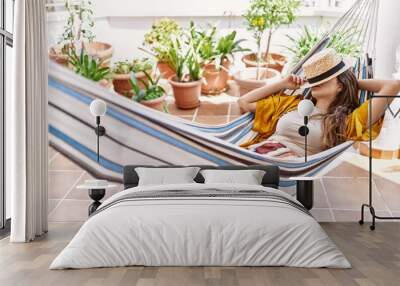 Young hispanic girl covering face with hat sleeping on hammock at the terrace. Wall mural