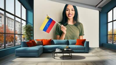 Young hispanic girl holding venezuelan flag looking positive and happy standing and smiling with a confident smile showing teeth Wall mural