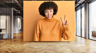 Young hispanic girl wearing wool winter sweater showing and pointing up with fingers number two while smiling confident and happy. Wall mural