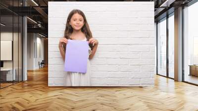 Young hispanic kid over white brick wall holding pink paper sheet with a happy face standing and smiling with a confident smile showing teeth Wall mural