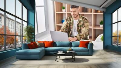 Young hispanic man army soldier using laptop sitting on table at home Wall mural