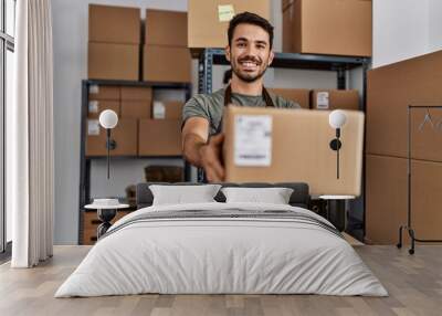 Young hispanic man business worker holding package at storehouse Wall mural