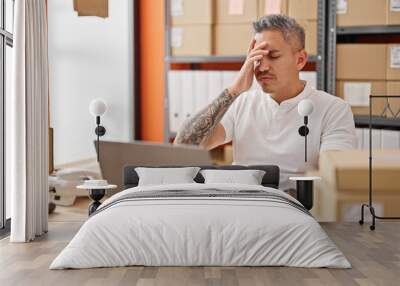 Young hispanic man ecommerce business worker using laptop stressed at office Wall mural