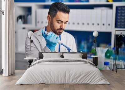 Young hispanic man scientist working at laboratory Wall mural