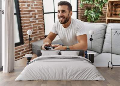 Young hispanic man smiling confident playing video game at home Wall mural