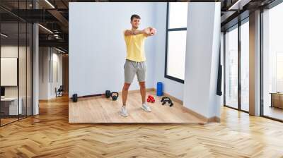 Young hispanic man smiling confident stretching arm at sport center Wall mural