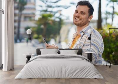 Young hispanic man smiling confident using smartphone at park Wall mural