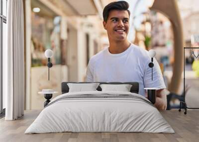 Young hispanic man smiling confident using smartphone at street Wall mural