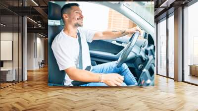 Young hispanic man smiling happy driving car. Wall mural