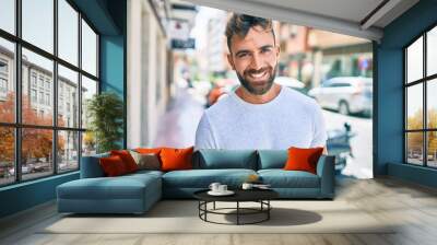 Young hispanic man smiling happy walking at the city Wall mural