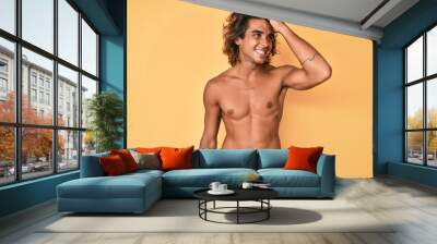 Young hispanic man standing shirtless smiling confident touching hair with hand up gesture, posing attractive and fashionable Wall mural