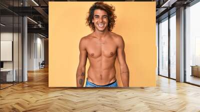 Young hispanic man standing shirtless winking looking at the camera with sexy expression, cheerful and happy face. Wall mural