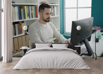 Young hispanic man student using computer studying at library university Wall mural