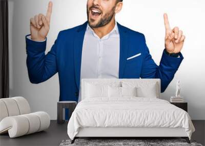 Young hispanic man wearing business jacket smiling amazed and surprised and pointing up with fingers and raised arms. Wall mural