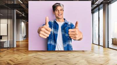 Young hispanic man wearing casual clothes approving doing positive gesture with hand, thumbs up smiling and happy for success. winner gesture. Wall mural