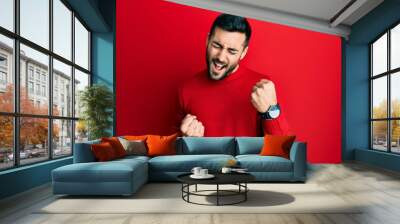 Young hispanic man wearing casual clothes celebrating surprised and amazed for success with arms raised and eyes closed Wall mural