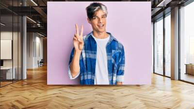 Young hispanic man wearing casual clothes showing and pointing up with fingers number two while smiling confident and happy. Wall mural