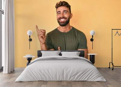 Young hispanic man wearing casual clothes smiling happy pointing with hand and finger to the side Wall mural