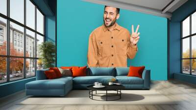 Young hispanic man wearing casual clothes smiling with happy face winking at the camera doing victory sign. number two. Wall mural