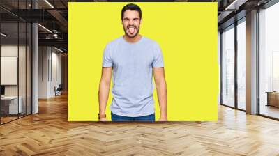 Young hispanic man wearing casual clothes sticking tongue out happy with funny expression. emotion concept. Wall mural