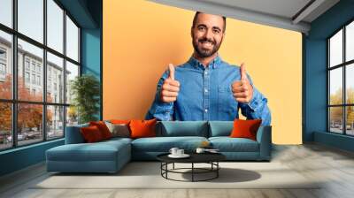 Young hispanic man wearing casual clothes success sign doing positive gesture with hand, thumbs up smiling and happy. cheerful expression and winner gesture. Wall mural