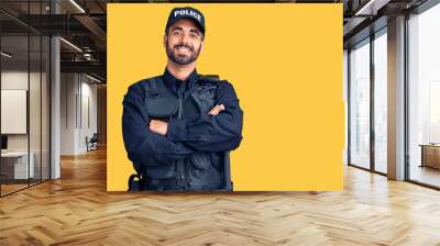 Young hispanic man wearing police uniform happy face smiling with crossed arms looking at the camera. positive person. Wall mural