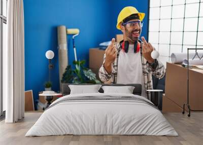 Young hispanic man with beard working at home renovation showing middle finger doing fuck you bad expression, provocation and rude attitude. screaming excited Wall mural