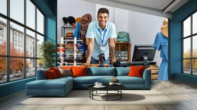 Young hispanic man working as shop assistant at retail shop Wall mural