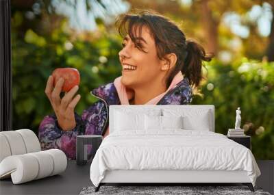 Young hispanic sporty woman smiling happy eating red apple at the park. Wall mural