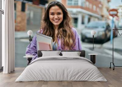 Young hispanic student woman smiling happy standing at the city. Wall mural