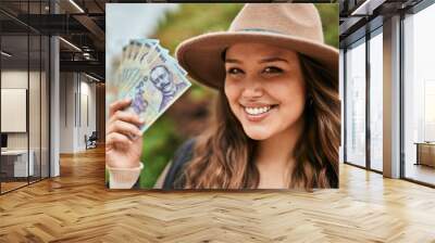 Young hispanic tourist woman smiling happy holding romania lei banknotes at the city. Wall mural