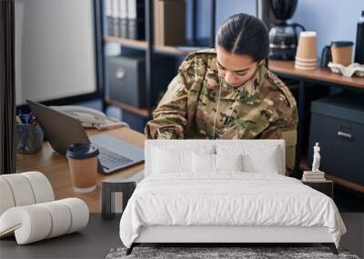 Young hispanic woman army soldier using laptop writing on document at office Wall mural