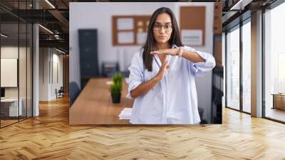 Young hispanic woman at the office doing time out gesture with hands, frustrated and serious face Wall mural