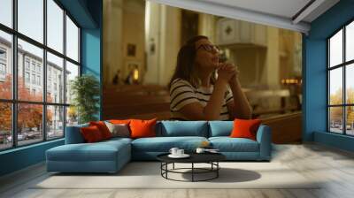 Young hispanic woman praying in a beautiful italian christian church, with a serene, spiritual atmosphere surrounding her. Wall mural