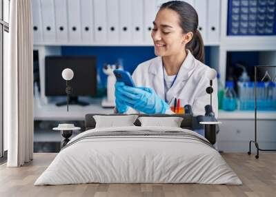 Young hispanic woman scientist using smartphone working at laboratory Wall mural