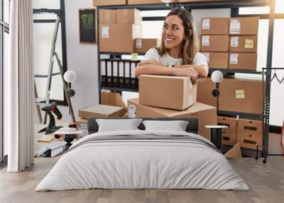 Young hispanic woman smiling confident leaning on delivery package at store Wall mural